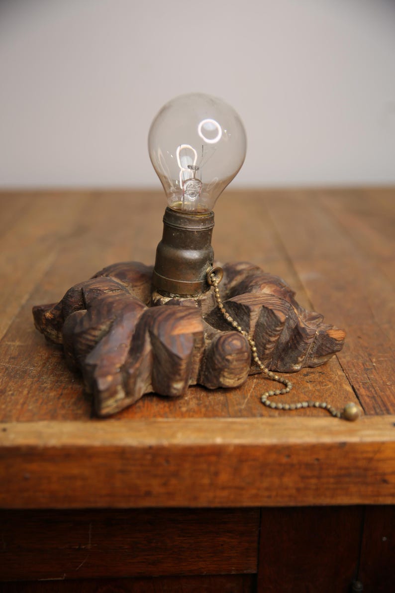 Puede incluir: Una base de l&aacute;mpara de madera con un dise&ntilde;o tallado y una bombilla adjunta. La l&aacute;mpara tiene una cadena de tracci&oacute;n para encender y apagar la luz.