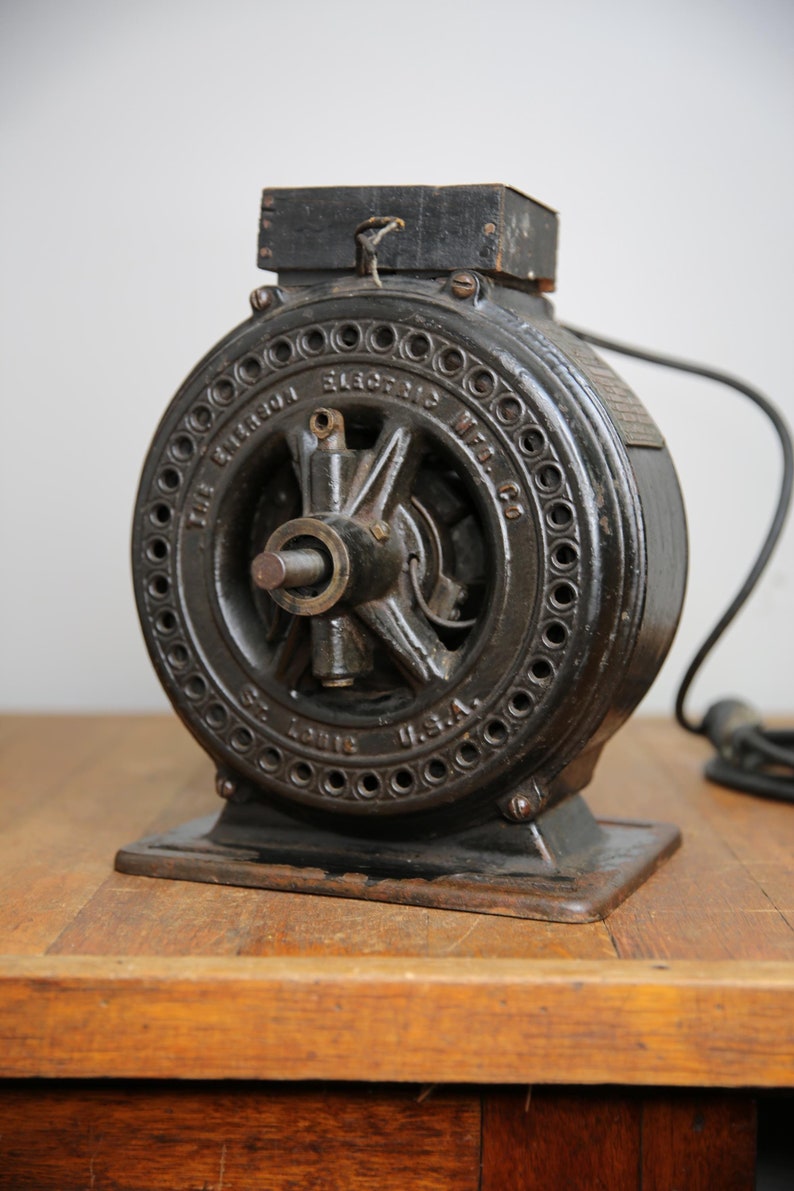 May include: A vintage black cast iron electric motor with the text "The Bilgram Electric Mfg. Co. St. Louis, U.S.A." on the side. The motor has a round base and a cord with a plug.