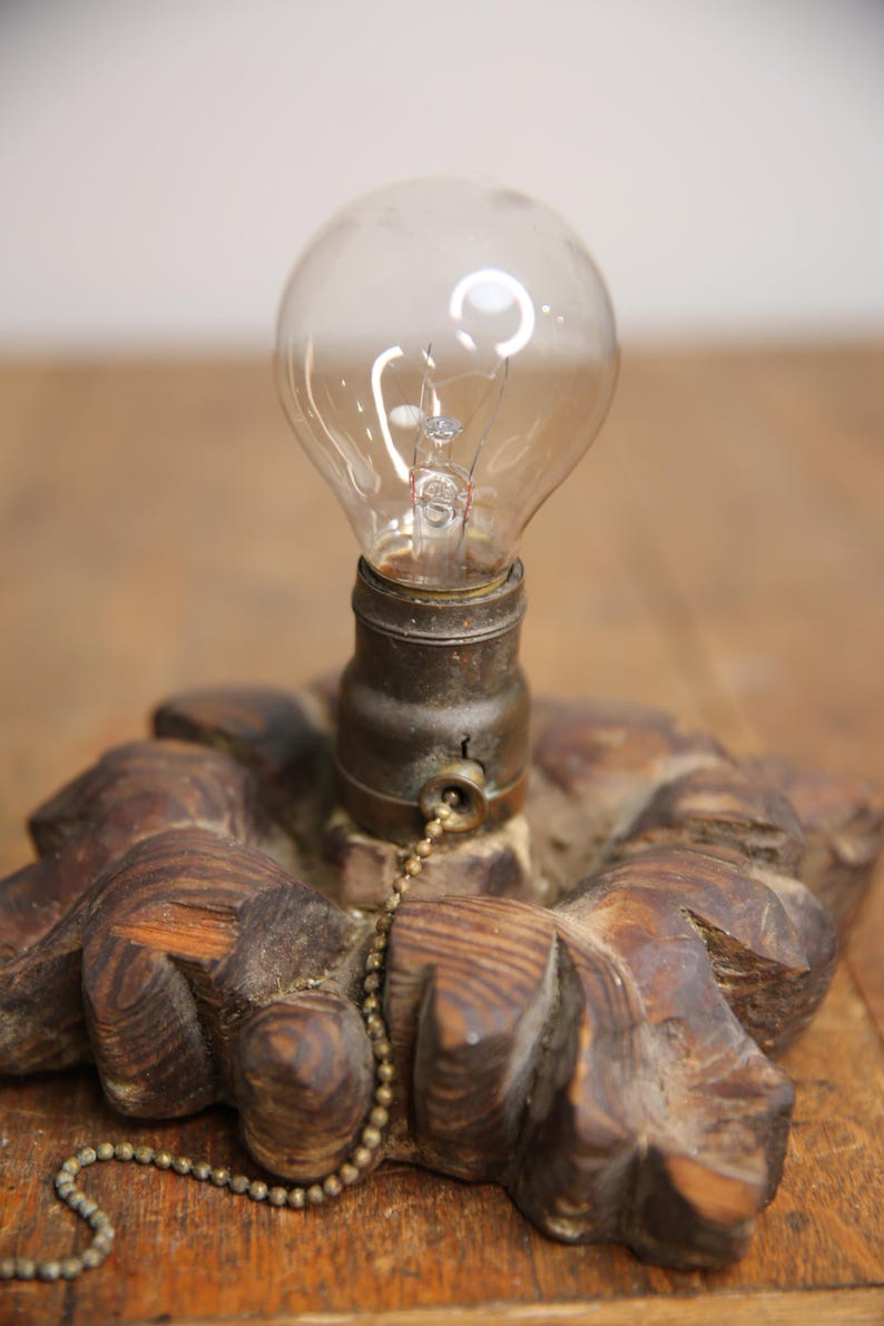 Puede incluir: Una base de l&aacute;mpara de madera con un dise&ntilde;o decorativo tallado. Una bombilla est&aacute; unida a la base con un interruptor de cadena.