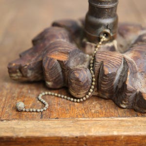 Puede incluir: Una base de l&aacute;mpara de madera con un interruptor de cadena. La base est&aacute; tallada con un dise&ntilde;o floral y tiene un acabado marr&oacute;n oscuro.