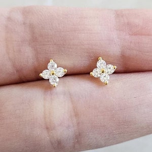 May include: A pair of gold-tone stud earrings with a four-leaf clover design. Each clover is adorned with five clear cubic zirconia stones.