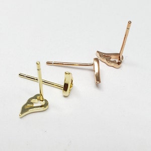 May include: A pair of gold heart-shaped earrings with a post back closure. The earrings are on a white surface.