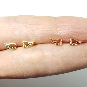May include: A pair of gold and rose gold angel wing earrings. The earrings are small and delicate, and they are perfect for everyday wear.