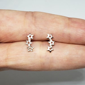 May include: A pair of silver star-shaped earrings. Each earring features five connected stars in a row.
