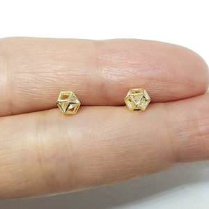 May include: A pair of gold geometric stud earrings with a clear crystal center.