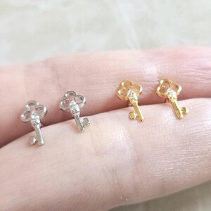 Puede incluir: Cuatro pendientes con forma de llave. Dos son plateados y dos dorados. Cada llave tiene una parte superior decorativa y una peque&ntilde;a gema transparente. Los pendientes son peque&ntilde;os y delicados.