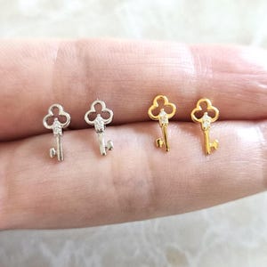 Puede incluir: Cuatro pendientes con forma de llave. Dos son de color plateado y dos dorados. Cada llave tiene una peque&ntilde;a gema transparente en la parte superior y un dise&ntilde;o de llave detallado. Los pendientes son peque&ntilde;os y delicados.