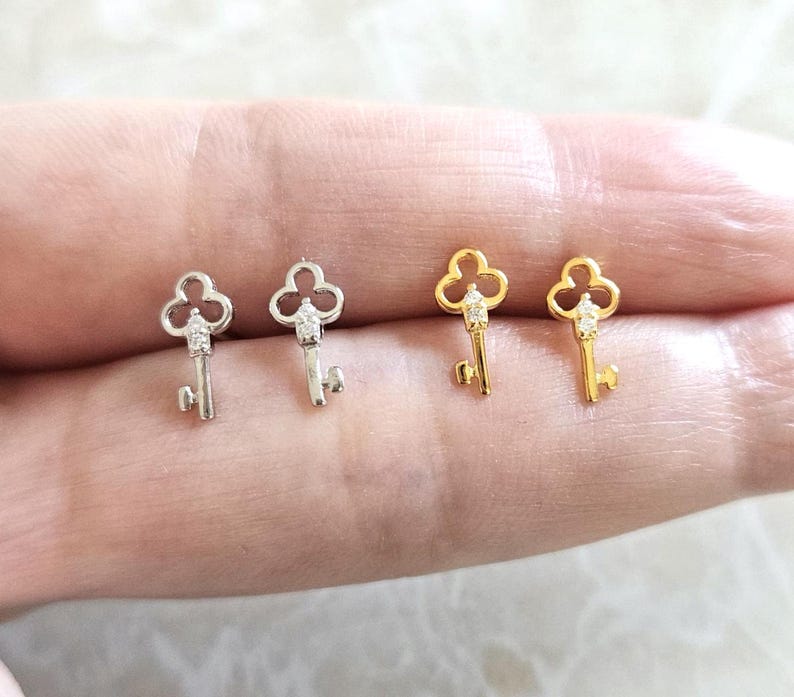 Puede incluir: Cuatro pendientes con forma de llave. Dos son de color plateado y dos dorados. Cada llave tiene una peque&ntilde;a gema transparente en la parte superior y un dise&ntilde;o de llave detallado. Los pendientes son peque&ntilde;os y delicados.
