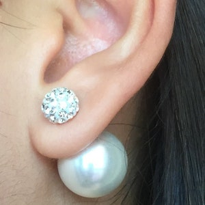 May include: A pair of earrings with a white pearl and a silver cluster of rhinestones.