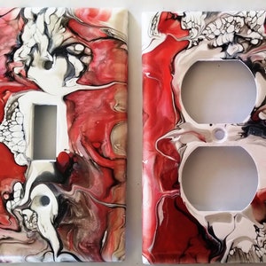 May include: Two decorative light switch covers. One cover has a single switch opening, the other has two outlet openings. Both covers feature a red, white, black, and gray abstract swirl design. The covers are made of a glossy material.