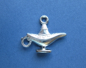 May include: A silver charm in the shape of a genie lamp. The lamp has a loop at the top for attaching to a bracelet or necklace.