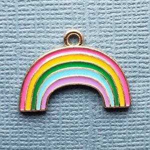 K&ouml;nnte beinhalten: Ein goldfarbener Regenbogen-Anh&auml;nger mit pinkfarbener, gelber, gr&uuml;ner, blauer und violetter Emaille-Oberfl&auml;che. Der Anh&auml;nger ist in Form eines Regenbogenbogens.