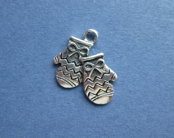 May include: Two silver-colored mitten charms with a bow detail at the top and a zig-zag pattern on the body. The charms are connected and have a loop at the top for hanging. The background is a solid blue color.
