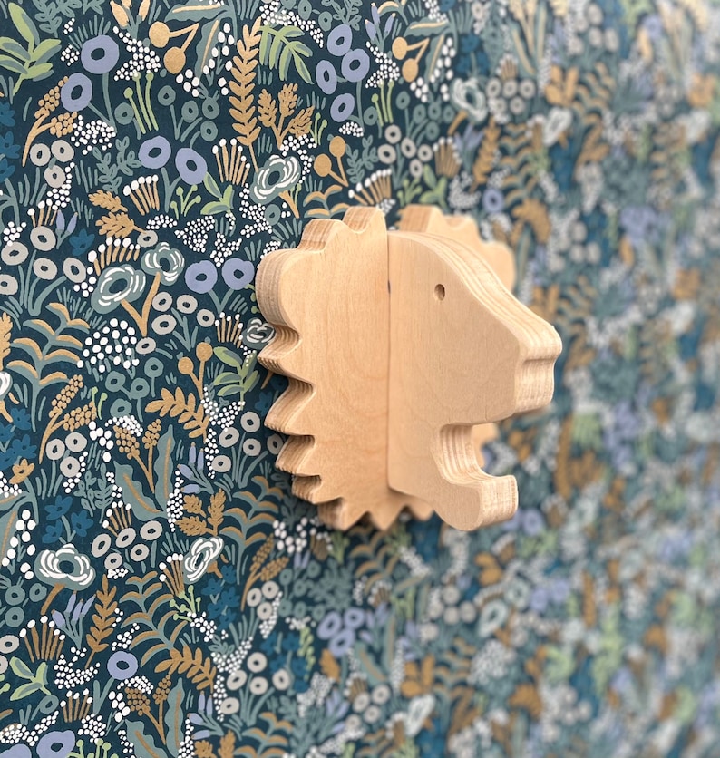 May include: A wooden lion head wall decor with a light brown finish. The lion head is carved with intricate details and has a whimsical, playful look. It is a great addition to a child's room or nursery.