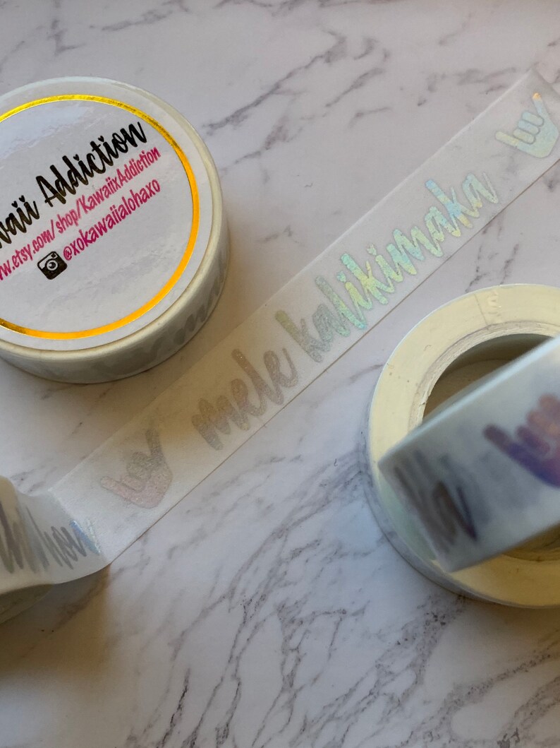 May include: Three rolls of white washi tape with holographic lettering. The tape reads "Kawaii Addiction", "@xokawaiailohaxo", and "mele kalikimaka".
