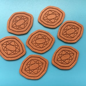 May include: Seven brown leather coasters with a geometric diamond design. The coasters are arranged in a circle on a blue surface.