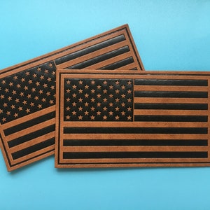 May include: Two brown leather patches with the American flag design. The flag is black and brown with white stars.