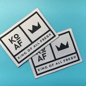 May include: Two white fabric labels with black text and a crown design. The top label reads "KO AF KING OF ALL FRESH". The bottom label reads "KO AF KING OF ALL FRESH".