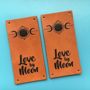 May include: Two brown leather labels with black text and a sun and moon design. The text on the labels reads "Love by Moon".