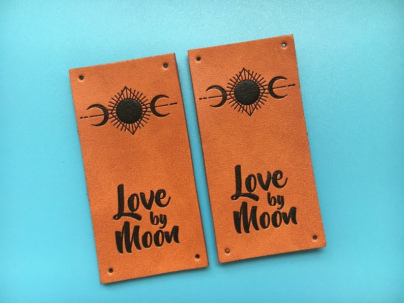 May include: Two brown leather labels with black text and a sun and moon design. The text on the labels reads "Love by Moon".