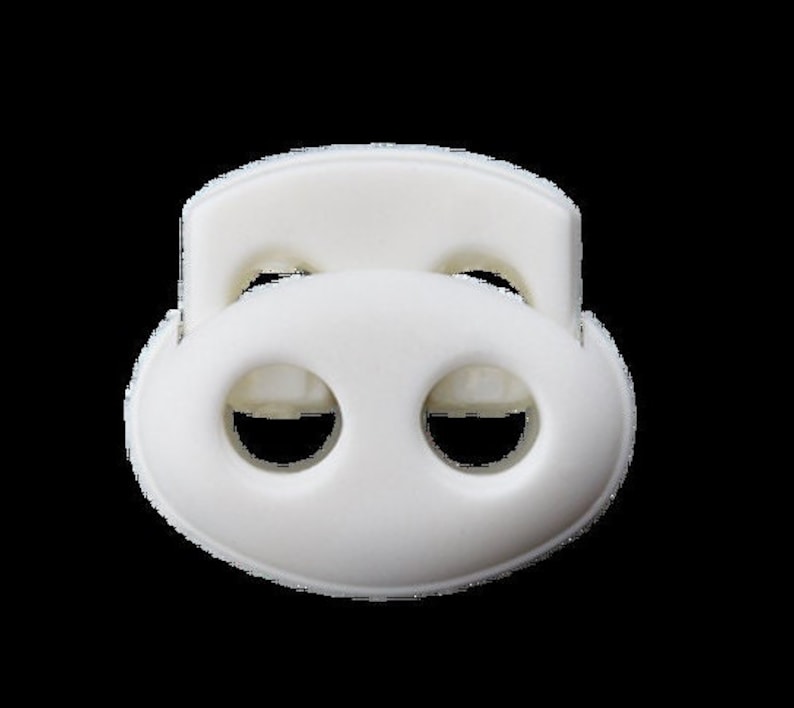 Puede incluir: Toggle de pl&aacute;stico blanco con dos agujeros. El toggle tiene forma ovalada y tiene un borde elevado en la parte superior.