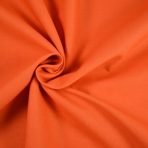 Könnte beinhalten: Nahaufnahme eines leuchtend orangenen Stoffes mit glatter Textur. Der Stoff ist gefaltet und drapiert und erzeugt weiche Falten und Kurven.