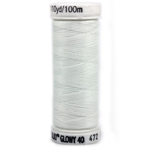 Op de afbeelding: Een spoel wit garen met de tekst "110yd/100m" bovenaan en "Sulky GLOWY 40 472" onderaan.
