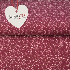 Könnte beinhalten: Ein Nahaufnahme eines pinkfarbenen Stoffes mit einem weißen Tupfenmuster. Der Stoff hat ein herzförmiges Etikett mit dem Text "SUMATEX Mit viel zum Detail".