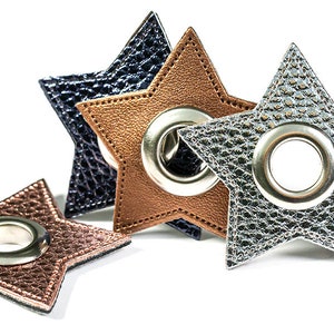Könnte beinhalten: Vier sternförmige Lederösen in Silber, Braun und Dunkelblau. Jede Öse hat einen silbernen Metallring in der Mitte.