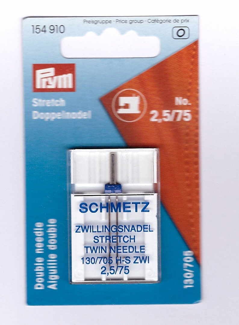 May include: A packet of Schmetz twin needles for stretch fabrics. The white plastic container holds two needles with blue accents. The packaging includes the text "Stretch Twin Needle" and "2.5/75". The package is blue and orange.