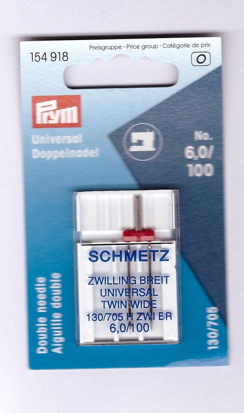 May include: A packet of SCHMETZ twin needles for sewing machines. The packaging is white and blue, with the brand name and needle specifications visible. The needles are labelled as 6.0/100, and the packet also includes the text "Double needle".
