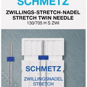 May include: A pack of Schmetz Stretch Twin Needles. The white package has blue accents and text. The needles are silver with blue plastic holders. The text on the package reads "SCHMETZ" and "STRETCH TWIN NEEDLE".