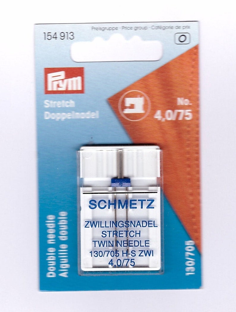 May include: A packet of Schmetz twin needles for stretch fabrics. The packaging is blue and orange, with the Prym logo and text in multiple languages. The needles are size 4.0/75, suitable for sewing stretch materials.
