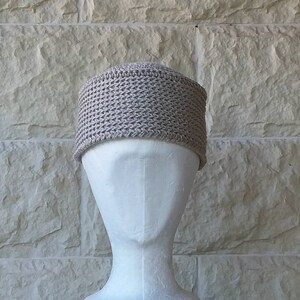 May include: A beige crocheted beanie hat on a white mannequin head.