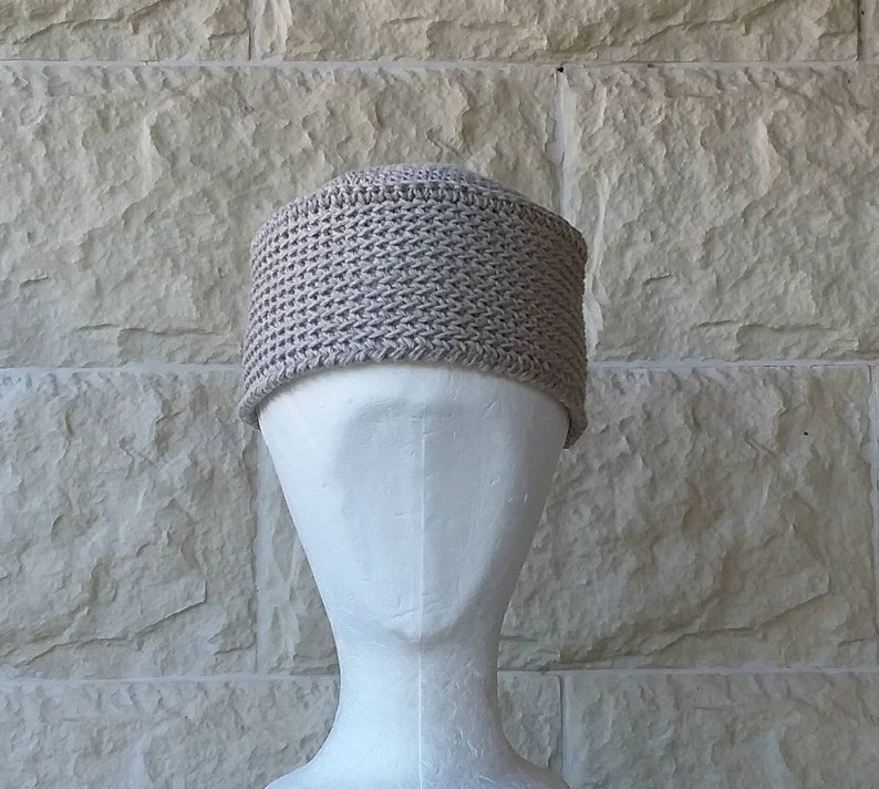 May include: A beige crocheted beanie hat on a white mannequin head.