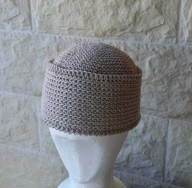 May include: A beige crocheted hat with a wide brim. The hat is made with a textured stitch and has a simple design.