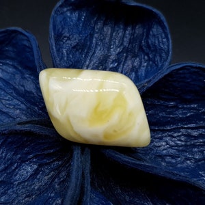 Pode incluir: Uma pedra de âmbar branca e amarela com forma de diamante, sobre um fundo azul.