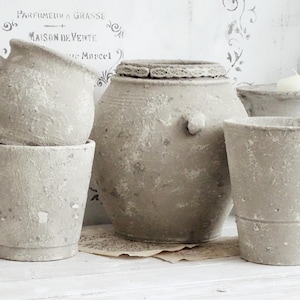 Puede incluir: Un juego de tres tazas de cerámica con un acabado moteado y mate. Las tazas son de color crema, gris claro y gris oscuro. Cada taza tiene un diseño simple y minimalista.