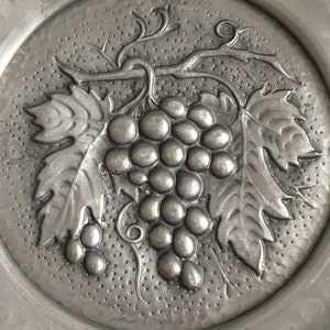 May include: A silver metal plate with an embossed design of a grapevine with leaves and grapes.