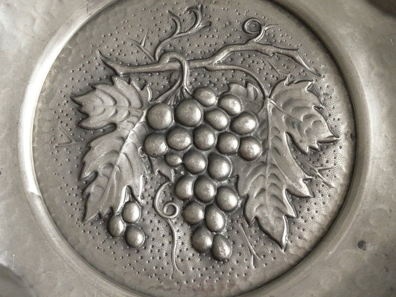 May include: A silver metal plate with an embossed design of a grapevine with leaves and grapes.