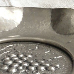 May include: A silver serving dish with a raised design of grapes and leaves.
