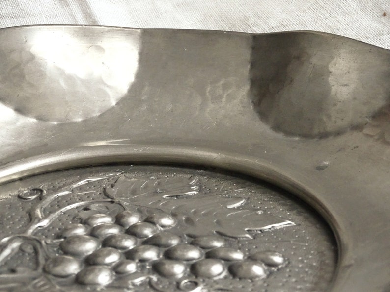 May include: A silver serving dish with a raised design of grapes and leaves.