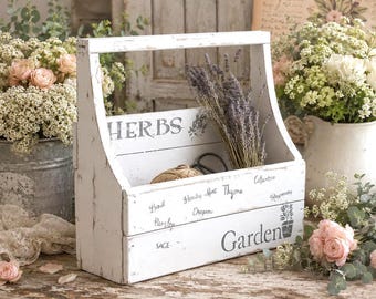 May include: A white wooden caddy with a distressed finish, featuring a handle and the printed text HERBS and Garden. The front panel lists various herbs including Basil, Parsley, Mint, Thyme, Oregano, Cilantro, Rosemary, and Sage in black lettering.