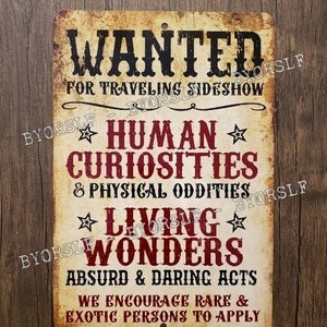 Può includere: Un cartello in metallo in stile vintage con uno sfondo usurato. Il cartello recita "WANTED FOR TRAVELING SIDESHOW HUMAN CURIOSITIES & PHYSICAL ODDITIES LIVING WONDERS ABSURD & DARING ACTS WE ENCOURAGE RARE & EXOTIC PERSONS TO APPLY".