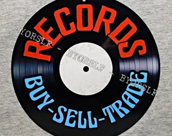 May include: A black vinyl record with the words "Records Buy-Sell-Trade" in blue and red lettering around the edge. The center of the record is white.