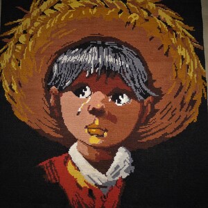 Peut inclure: Une image au point d'aiguille d'un jeune portant un chapeau de paille brun. La personne a les cheveux foncés et la peau brune et pleure. La personne porte une chemise rouge et blanche.