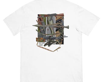 May include: White t-shirt with a graphic of various military weapons, including a rifle, a machine gun, and ammunition. The graphic is in a camouflage pattern and includes the text "Cold War Armor".