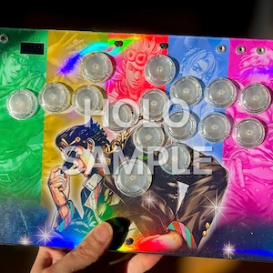 Peut inclure: Un stick arcade personnalis&eacute; avec un design color&eacute; repr&eacute;sentant des personnages d'anime. Les boutons transparents sont dispos&eacute;s selon une disposition standard. L'&oelig;uvre d'art a un effet holographique, et le texte "HOLO SAMPLE" est visible.