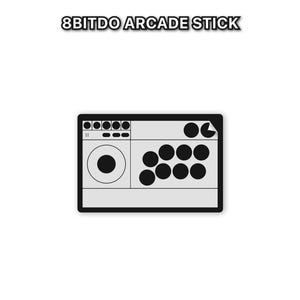 Peut inclure: Un stick d'arcade 8Bitdo gris avec des boutons noirs et un joystick. Le texte "8BITDO ARCADE STICK" est au-dessus du stick d'arcade. Le stick d'arcade a une bordure noire et est sur fond blanc.
