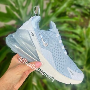 Puede incluir: Zapatillas Nike Air Max 270 de color azul claro con un swoosh blanco y una suela de burbuja de aire transparente. El swoosh est&aacute; decorado con diamantes de imitaci&oacute;n transparentes.